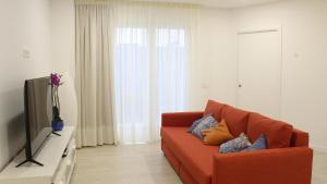 - un salon avec un canapé orange et une télévision dans l'établissement Piso Lagunero Acogedor, à La Laguna