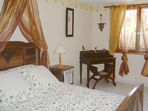 a bedroom with a bed and a table and a desk at la roseraie in Caumont