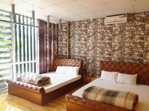 a bedroom with two beds and a leather couch at Long Hotel and motobike rental in Ha Giang