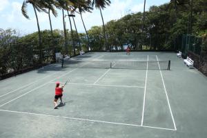 two people playing tennis on a tennis court at Young Island Resort in Kingstown