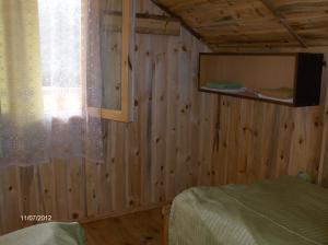 sypialnia z drewnianymi ścianami, łóżkiem i oknem w obiekcie Guest House Mirgvela w mieście Omalo