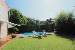 un patio trasero con una piscina con 2 sillas y una mesa en Bonita villa pareada con piscina privada en San Sebastián
