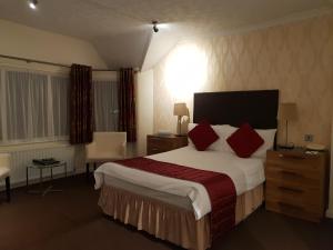 道格拉斯的住宿－阿斯科特酒店，酒店客房配有一张带红色枕头的大床