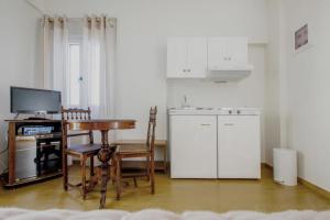 a kitchen with a table and a desk and a kitchen with white cabinets at Emilia Luxury Apartments in Megas Yialos-Nites