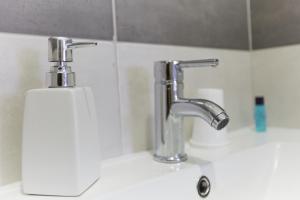 - un lavabo avec deux robinets et un distributeur de savon dans l'établissement Residencial Principe Guest House, à Barreiro