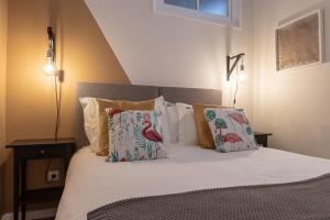 um quarto com uma cama com lençóis brancos e almofadas em Carnot House em Setúbal