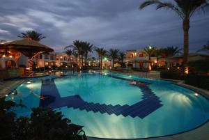 a pool at night with palm trees and buildings at Coral Hills Resort Sharm El-Sheikh in Sharm El Sheikh