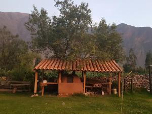 Mágico lugar en el Valle Sagrado في كوسكو: شرفة بها شجرة فوق حقل