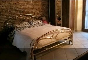 a metal bed in a room with a brick wall at Taverna rustica in Toscana in Fucecchio