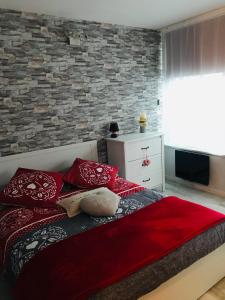 een slaapkamer met een bed met rode kussens en een bakstenen muur bij Le Belvédère - GÎTES MARCK in Turckheim