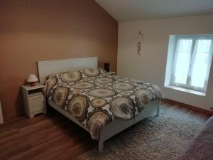 a bedroom with a bed with a comforter and a window at Les Portes de Champagne in Bassevelle