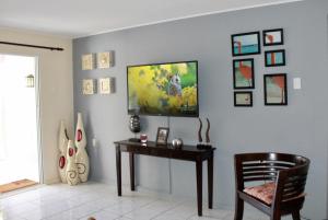 Habitación con mesa y TV en la pared. en Bon Bini na Curacao, en Willemstad