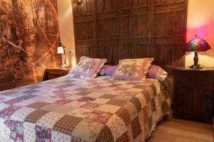 ein Schlafzimmer mit einem Bett mit einer Decke und einer Lampe in der Unterkunft Apartamentos Jardines de Llanes in Pancar