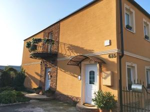 a yellow building with a white door and a balcony at Apartmány Kord in Lednice