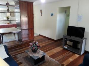 a living room with a couch and a tv at Suites do Reino Penedo RJ in Penedo