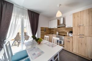 a kitchen with a white table and chairs and a window at Apartments LeonDori in Krk