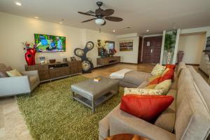 a living room with couches and a ceiling fan at Expectacular Penthouse frente al Mar con Jacuzzi in Jacó