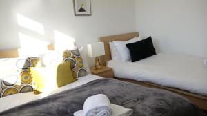 a bedroom with a white bed and a white comforter at Airport Garden Rooms in Feltham