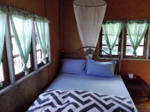 a bed in a room with two windows at Oceanblue Guesthouse in Ko Chang