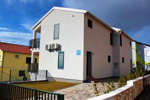 Biały budynek z niebieskimi okiennicami w obiekcie Divine Dalmatia Apartments 2 w mieście Tribunj