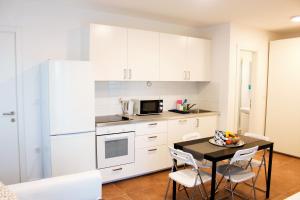 een keuken met witte kasten en een tafel met stoelen bij Divine Dalmatia Apartments 2 in Tribunj
