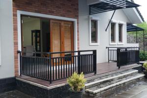 une terrasse couverte à l'avant d'une maison avec une balustrade noire dans l'établissement Pesona Air - Villa and Private Pool, à Depok