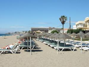 a row of lawn chairs and umbrellas on a beach at Balcon Del Mar Primera Linea de Playa in La Cala de Mijas