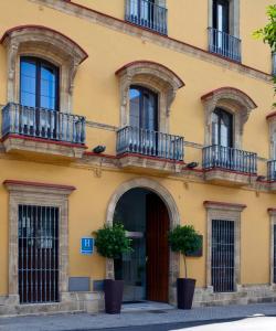 un edificio amarillo con balcones y una puerta en Itaca Jerez by Soho Boutique, en Jerez de la Frontera
