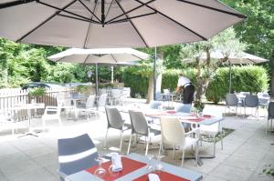 un patio con mesas, sillas y sombrillas en Enzo Hôtels Premier Prix - Logis Amnéville, en Amnéville