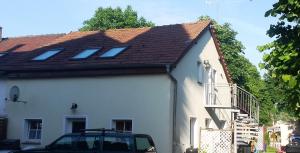 a white house with a roof and a car parked next to it at Ferienwohnung Hoffmann Grossdeuben DG in Böhlen