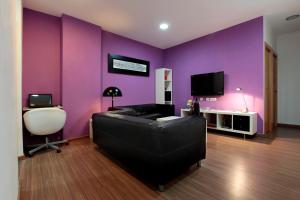 Dieses lila Zimmer verfügt über ein Sofa und einen TV. in der Unterkunft Hostal Nitzs Bcn in Barcelona