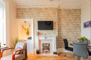 sala de estar con pared de ladrillo y chimenea en Clyde View Apartment en Helensburgh