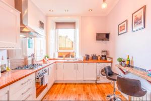 a large kitchen with white cabinets and a window at Clyde View Apartment in Helensburgh