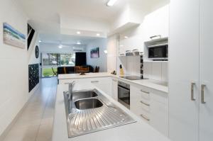 una cocina con fregadero de acero inoxidable en el centro en TiTree Village Holiday Apartments, en Port Douglas