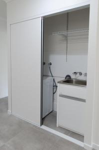 una cocina con armarios blancos y fregadero en TiTree Village Holiday Apartments, en Port Douglas