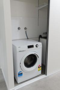 Una lavadora y secadora en una habitación blanca en TiTree Village Holiday Apartments, en Port Douglas