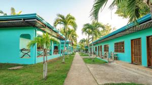 a blue building with palm trees next to a sidewalk at Bohol Sea Resort in Panglao