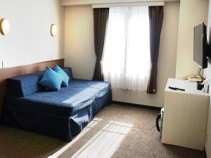 ein Wohnzimmer mit einem blauen Sofa und einem Fenster in der Unterkunft Hotel Abest Happo Aldea in Hakuba