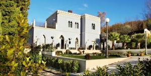 una gran casa blanca con árboles y arbustos en Relais La Placa, en Francavilla di Sicilia