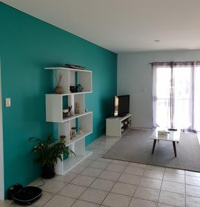 uma sala de estar com uma parede azul e uma televisão em Blue horizon em Yeppoon