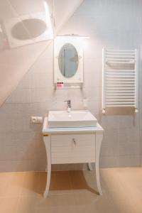 a white bathroom with a sink and a mirror at Royal Bakuriani in Bakuriani