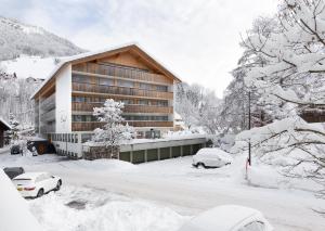 ein schneebedecktes Gebäude mit davor geparkt in der Unterkunft Hotel Engel in Mellau