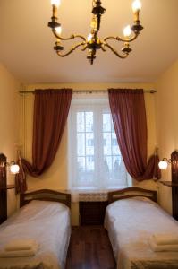 two beds in a room with a window and a chandelier at Apartament Parkowy in Sandomierz