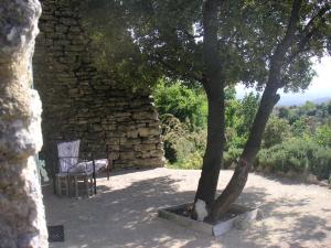 una silla y un árbol junto a una pared de piedra en Le Jardin d'Adam, en Gordes