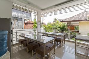 a dining room with tables and chairs on a balcony at Ara Inn Bed And Breakfast by ecommerceloka in Kuta