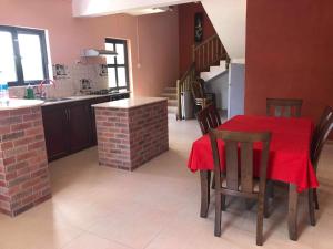 a kitchen and dining room with a red table and chairs at Aashsweet Villa in Calodyne