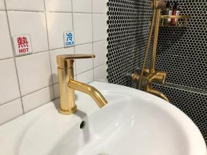 un lavandino bianco con rubinetto d'oro in bagno di 一個好人民宿 青年旅舍衛浴共用的超級小隔間 花蓮縣民宿2410號 a Città di Hualien Altre 19 foto