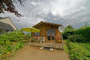 Cabaña de madera pequeña con mesa y sombrilla en Chalet, en Plouër-sur-Rance