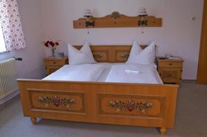 a large wooden bed with white sheets and pillows at Gästehaus Donautal in Vichtenstein