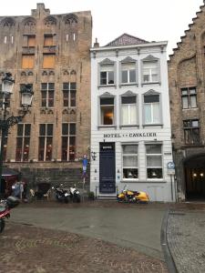 a white building with a motorcycle parked in front of it at Hotel Cavalier in Bruges